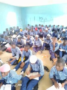 Students writing while sitting on the floor at Government Comprehensive Day Secondry School (GCDSS), Bakari Dukku, Bauchi LGA.